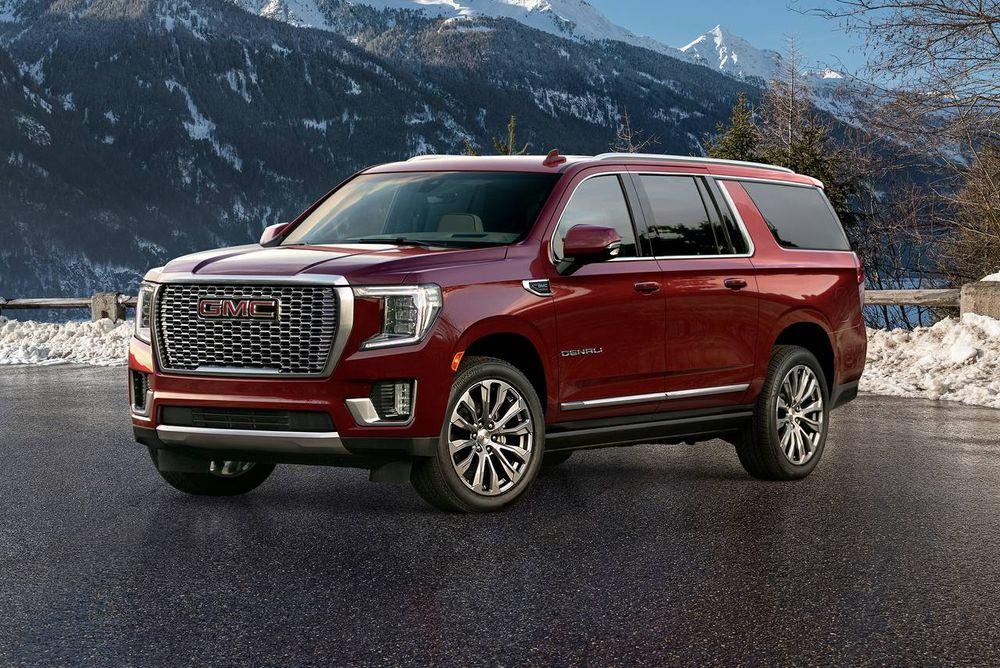 Crimson GMC Yukon parked on snowy road with mountains in the background