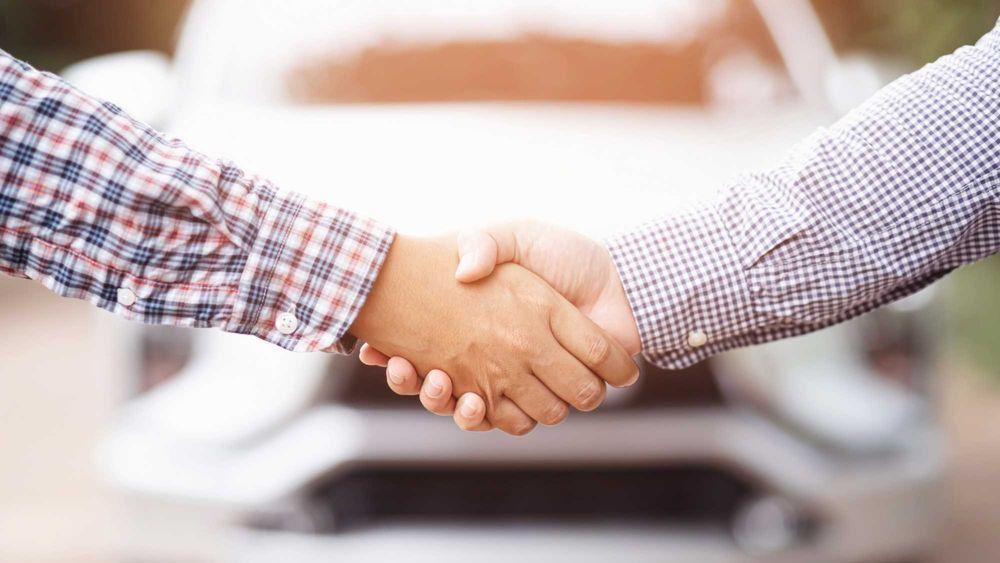 two guys shaking hands after selling a car privately