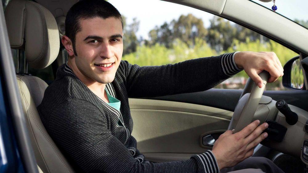 Young Driver behind the wheel of the car he is selling for the first time