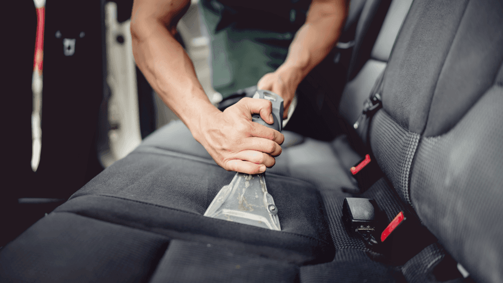 Guy detailing and vacuuming the inside of a car to sell it online