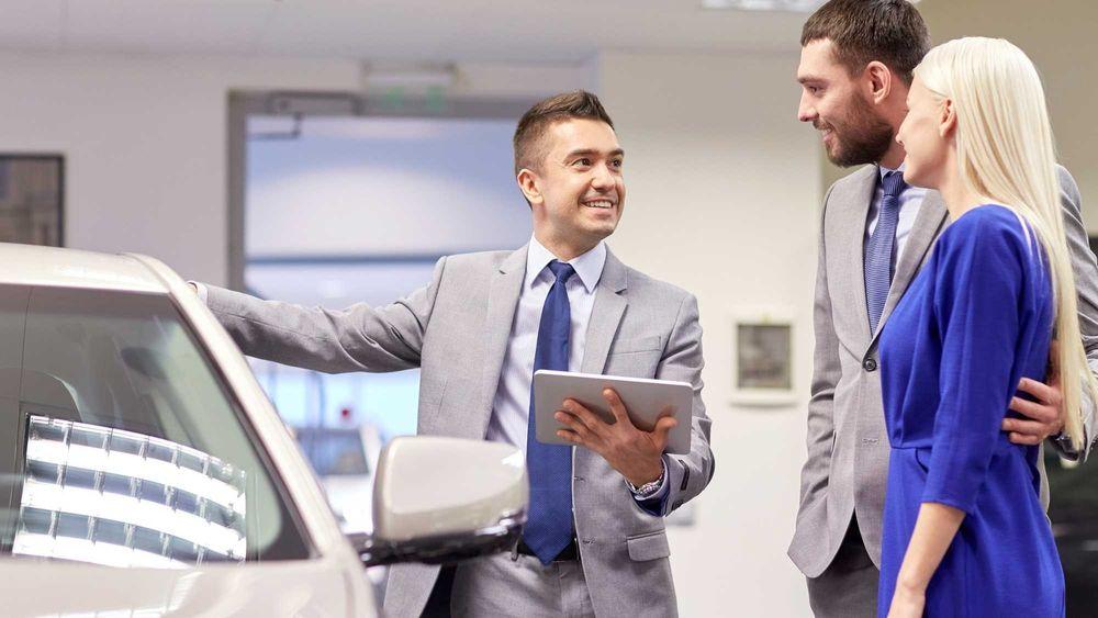 Couple discussing buying a car with the salesman at the dealership