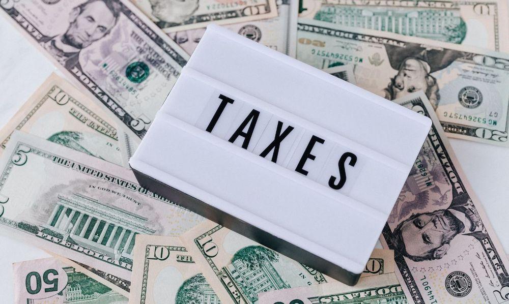 A sign with the word Taxes on top of money