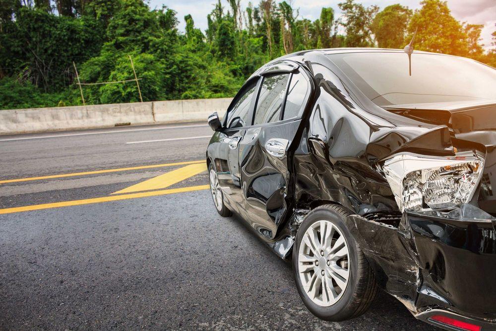 Black car in car accident in the middle of a main road.