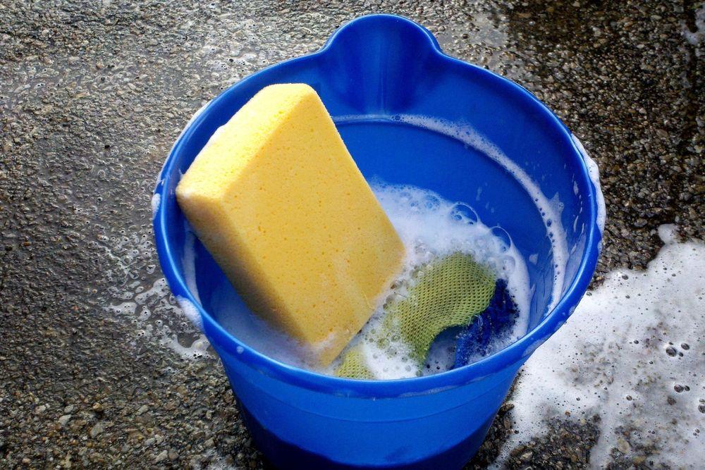 Bucket of soapy water and a sponge on wet asphalt