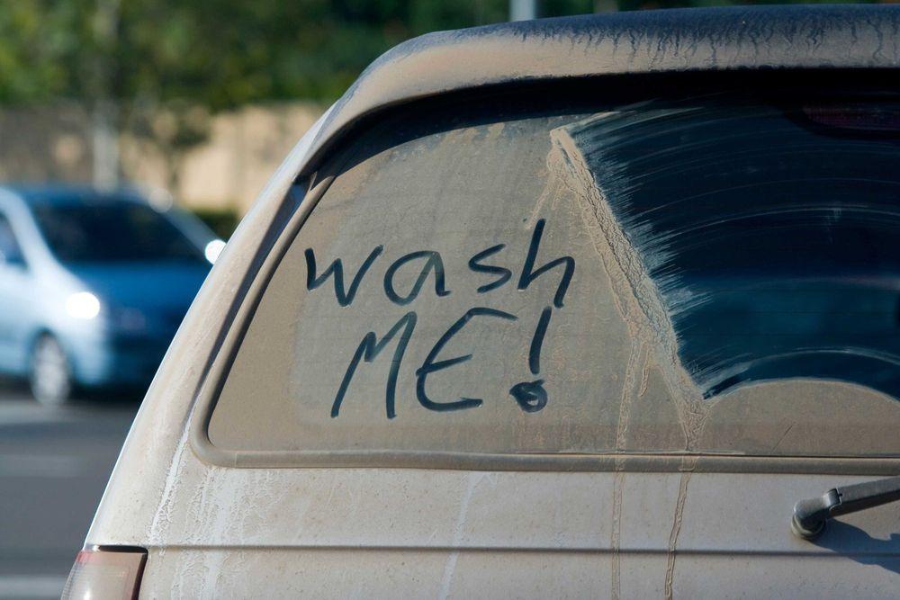 Dirty car that says wash me on the back window.