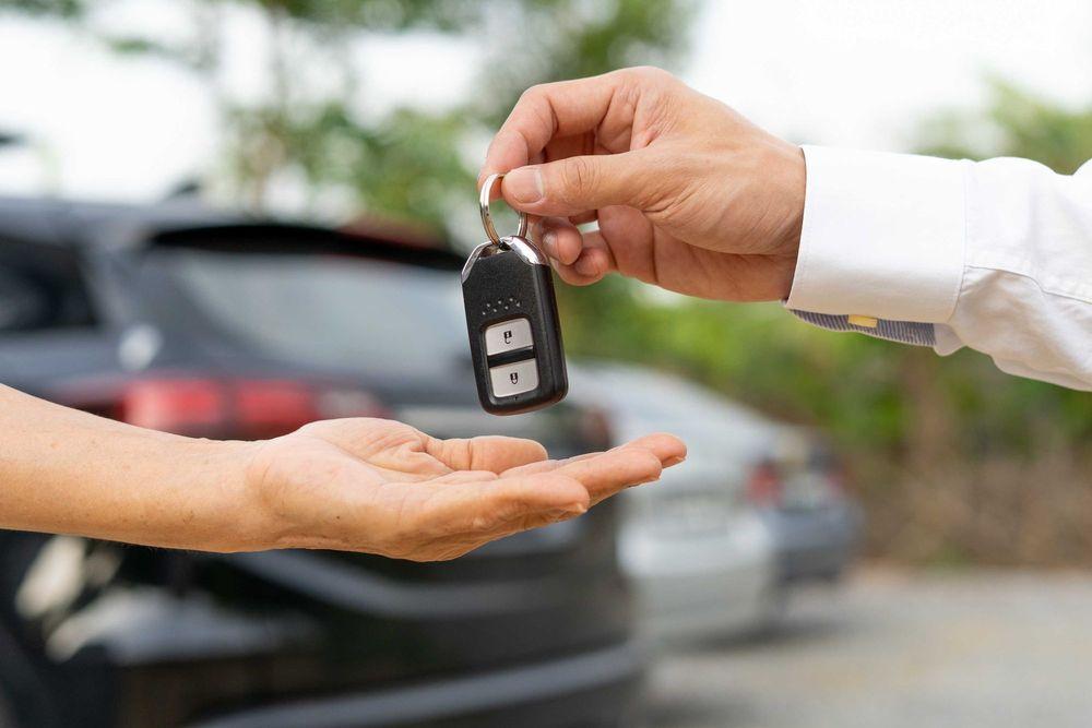 Person handing over a pair of car keys to another person