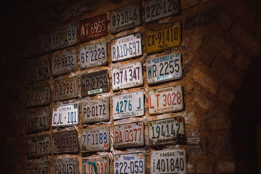 Brick wall with license plates hung on it.