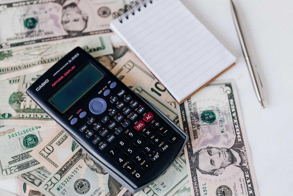 Calculator and note pad on top of cash money.