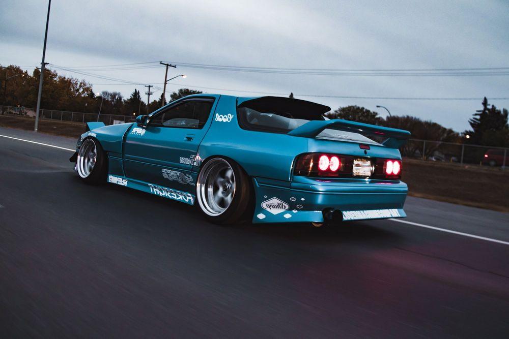 Blue Mazda RX-7 driving on the road.