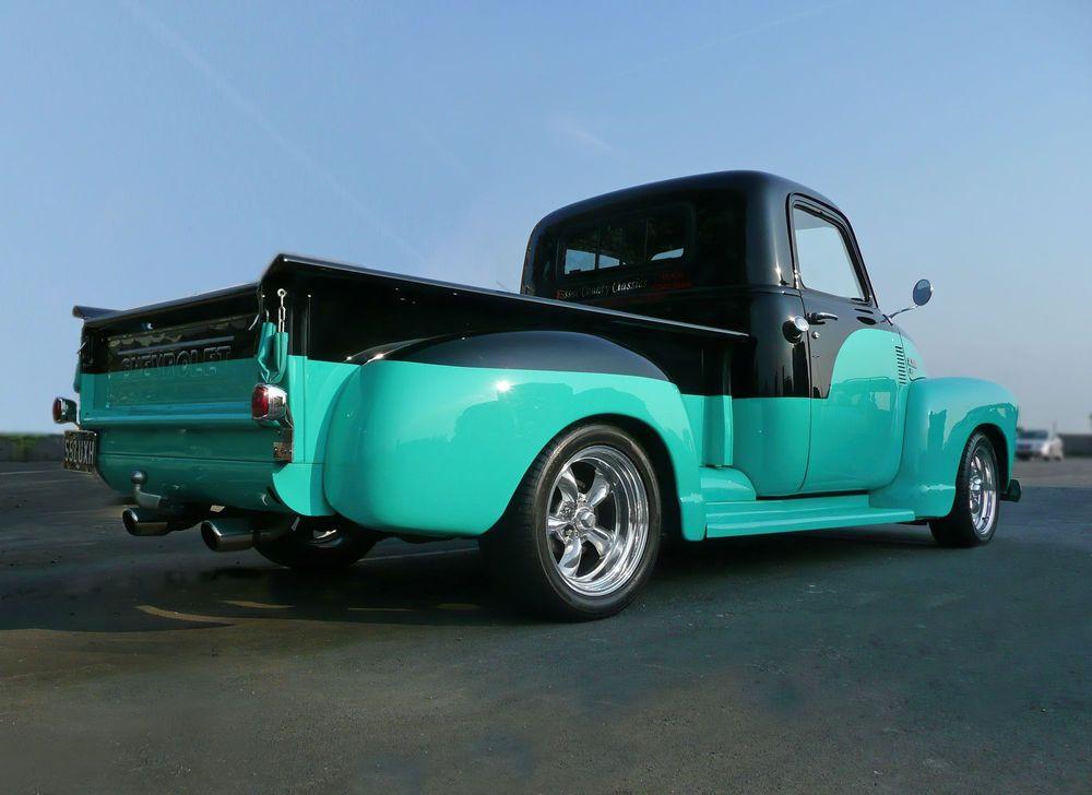 Black and teal custom truck parked on black top.
