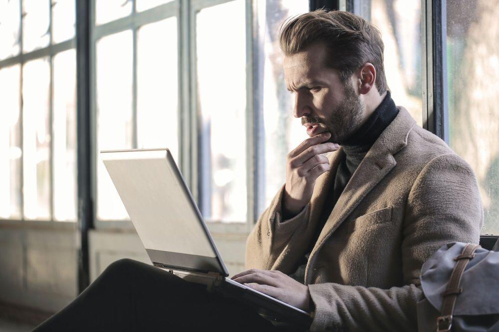 Man in jacket working on laptop.