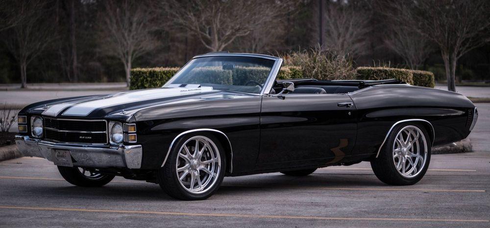 Black classic convertible car with the top down in a parking lot.