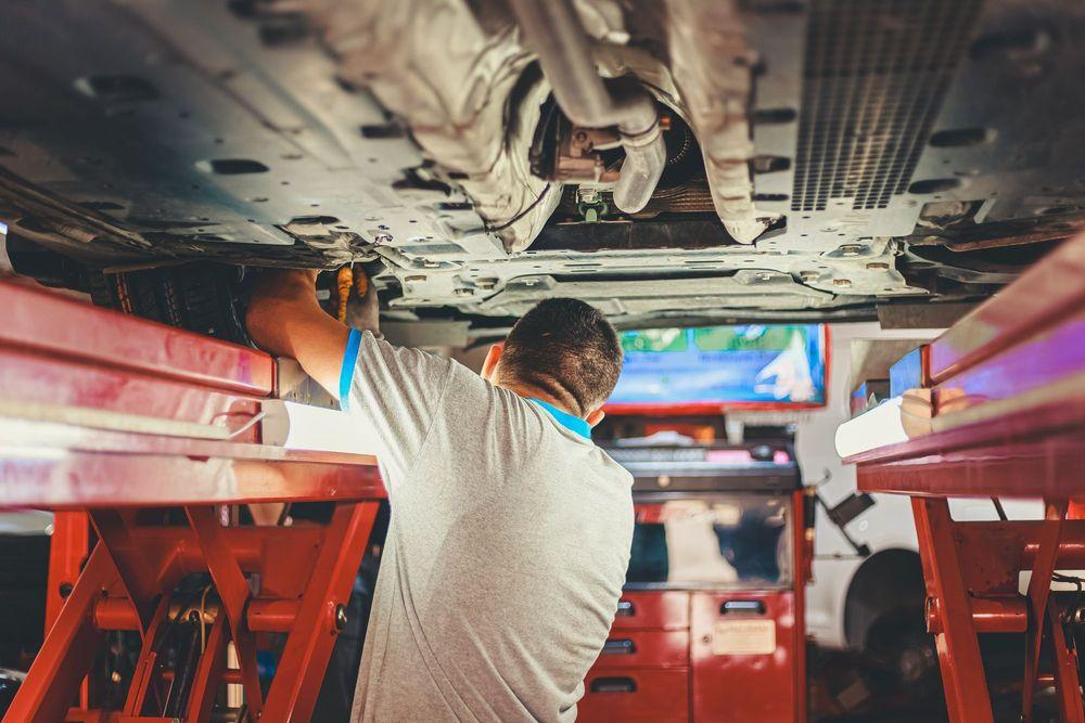 Mechanic working on the underside of a car.