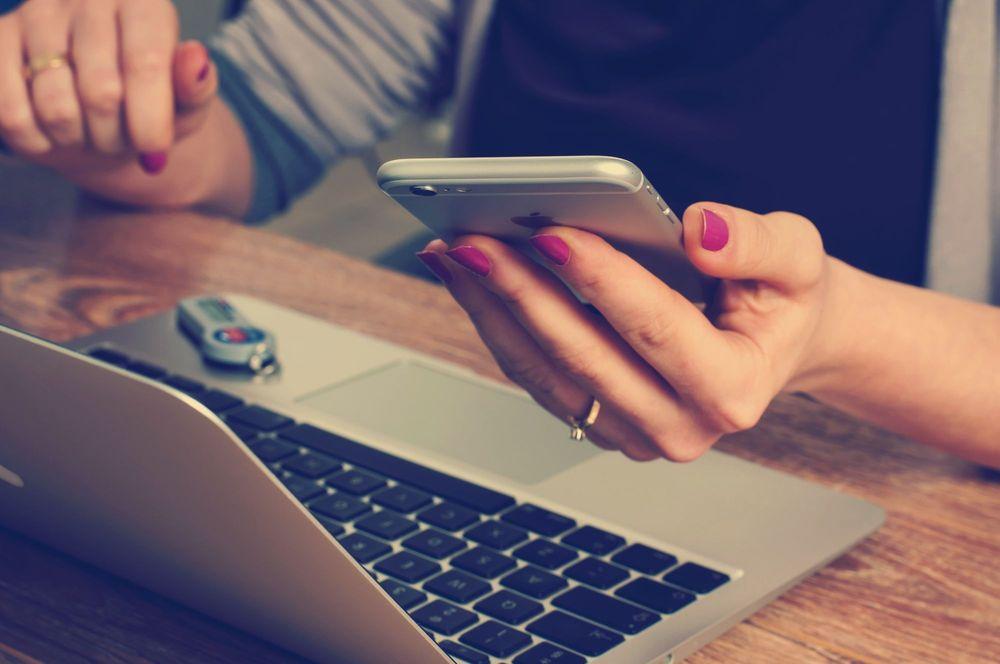 Girl looking at smartphone and laptop.