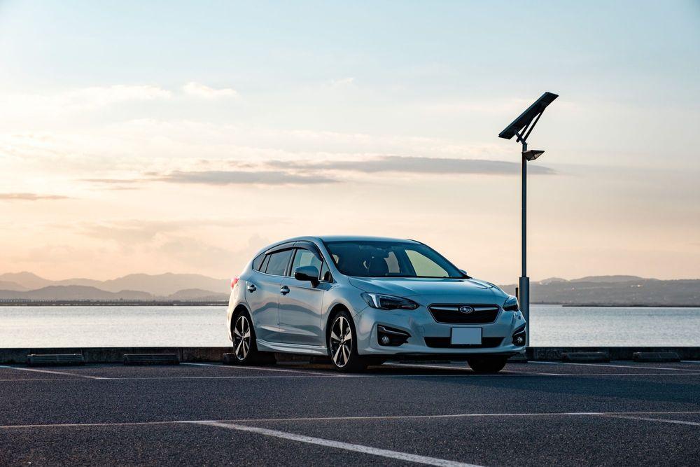 White Subaru Impreza parked in front of a lake.