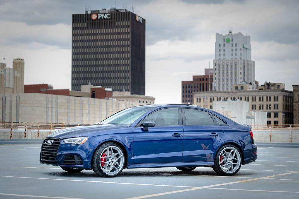 Blue Audi parked on top level of parking garage.
