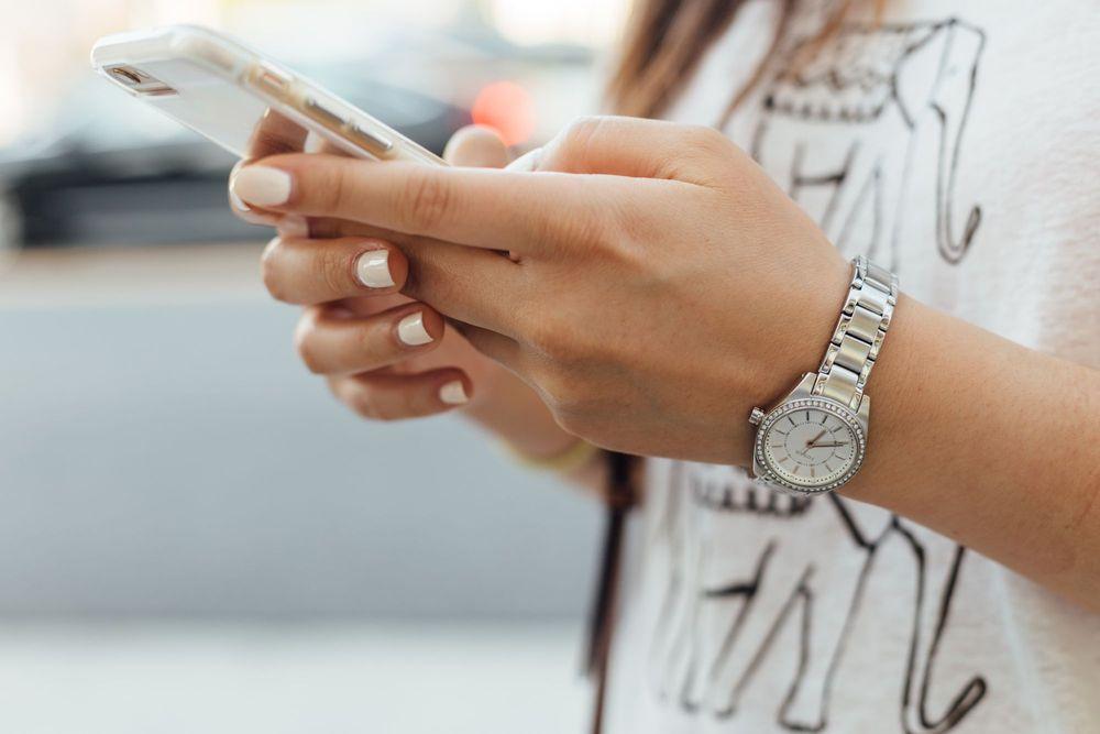 Girl with silver watch looking at smartphone.