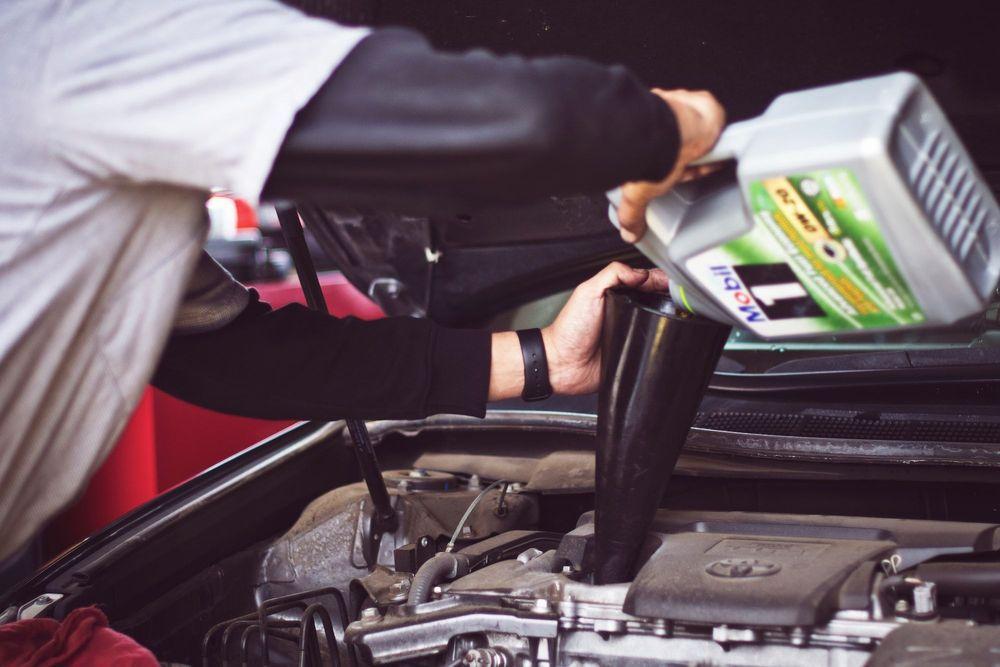 car mechanic giving a car an oil change in preparation to sell it 