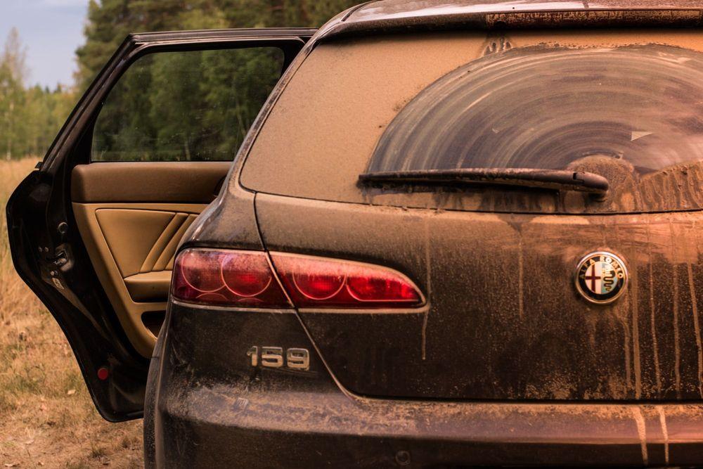 The back of a really Dirty car with the drivers side door open