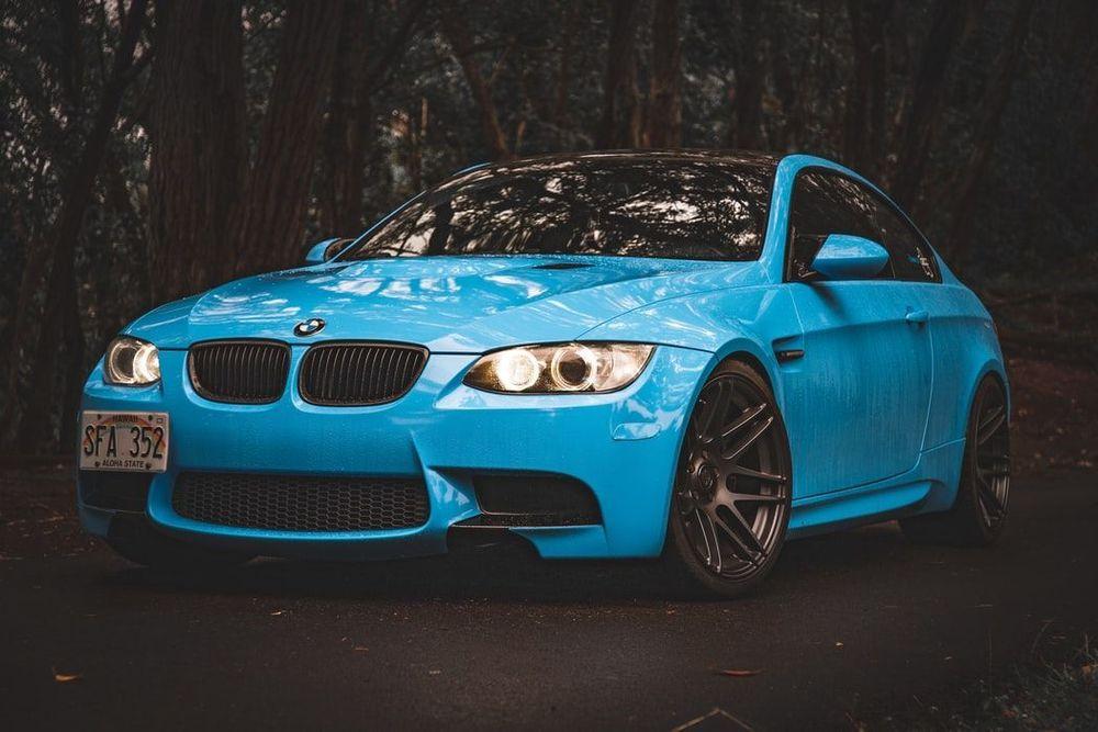 Light Blue BMW sports car on a dark woodsy background
