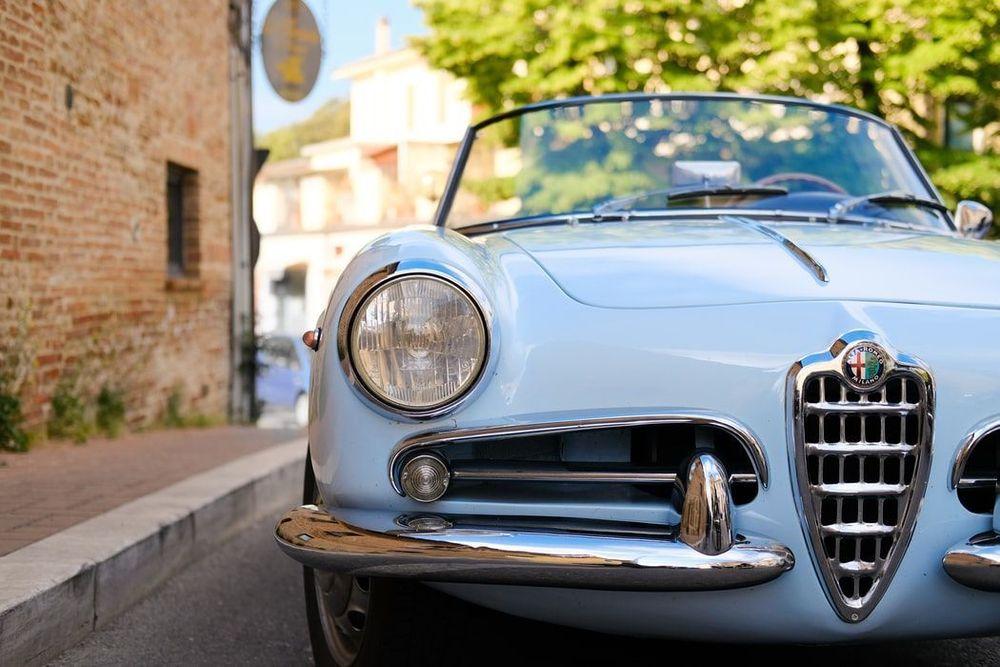 front end of a Valuable blue classic car parked in front of a brick building