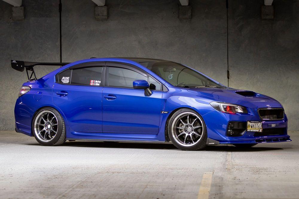 Blue custom car with spoiler in parking garage.