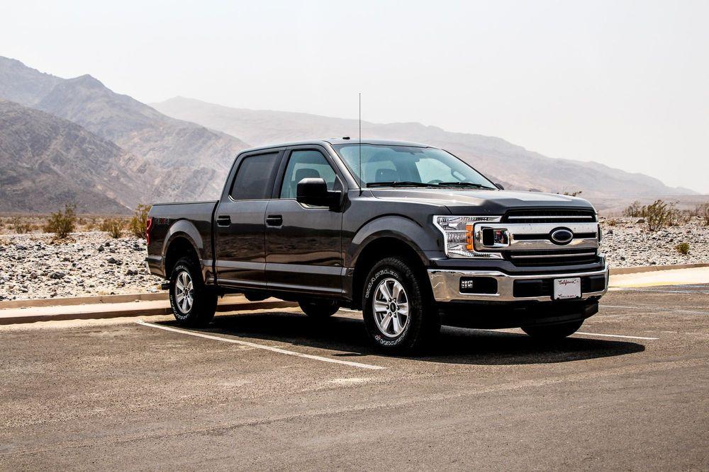 Black truck parked in parking lot in front of mountains.