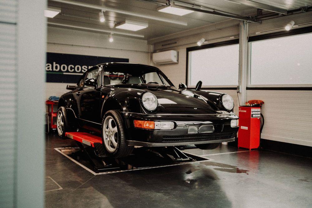 Nice black Porsche lifted in car garage. 