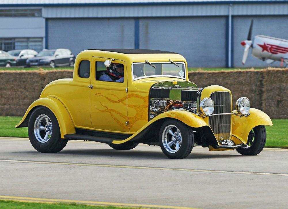 Yellow hot rod with flames driving on the road.